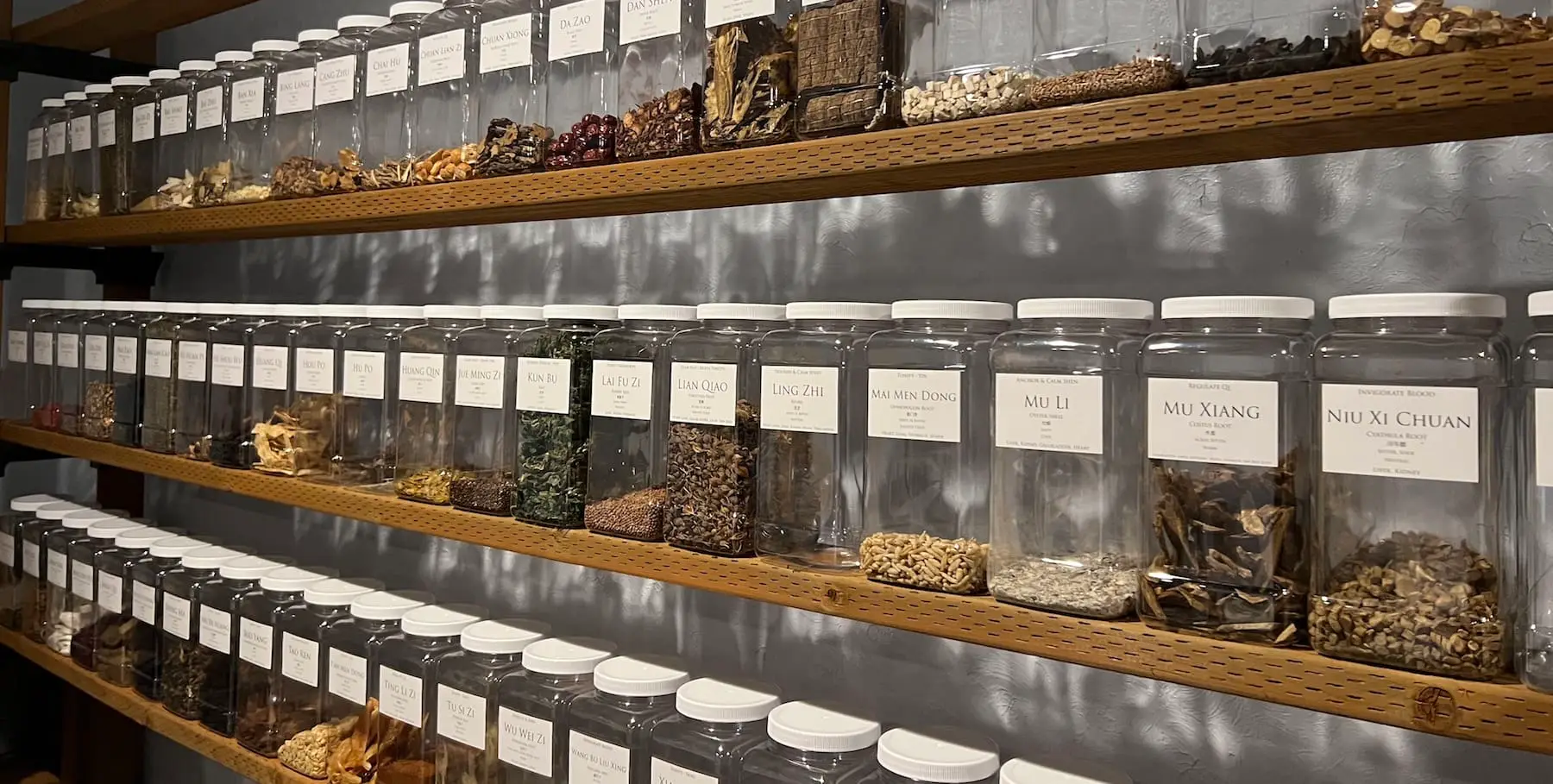 three rows of shelves in the herbal apothecary at Jing Shen Healing Arts displaying the herbal items used to create personalized herbal remedies for their patients